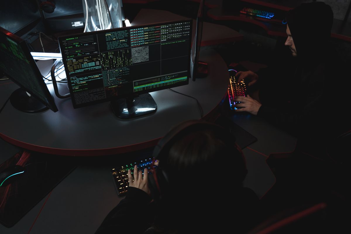 Source photo of people working at computers in a dark operations environment